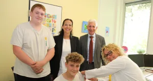 Dörthe Erdmann impft den 14-jährige Maximilian unter den Blicken seines Bruders Bastian, Kreisrätin Ana Cristina Bröcking und Landrat Rainer Rempe. Foto: Landkreis Harburg